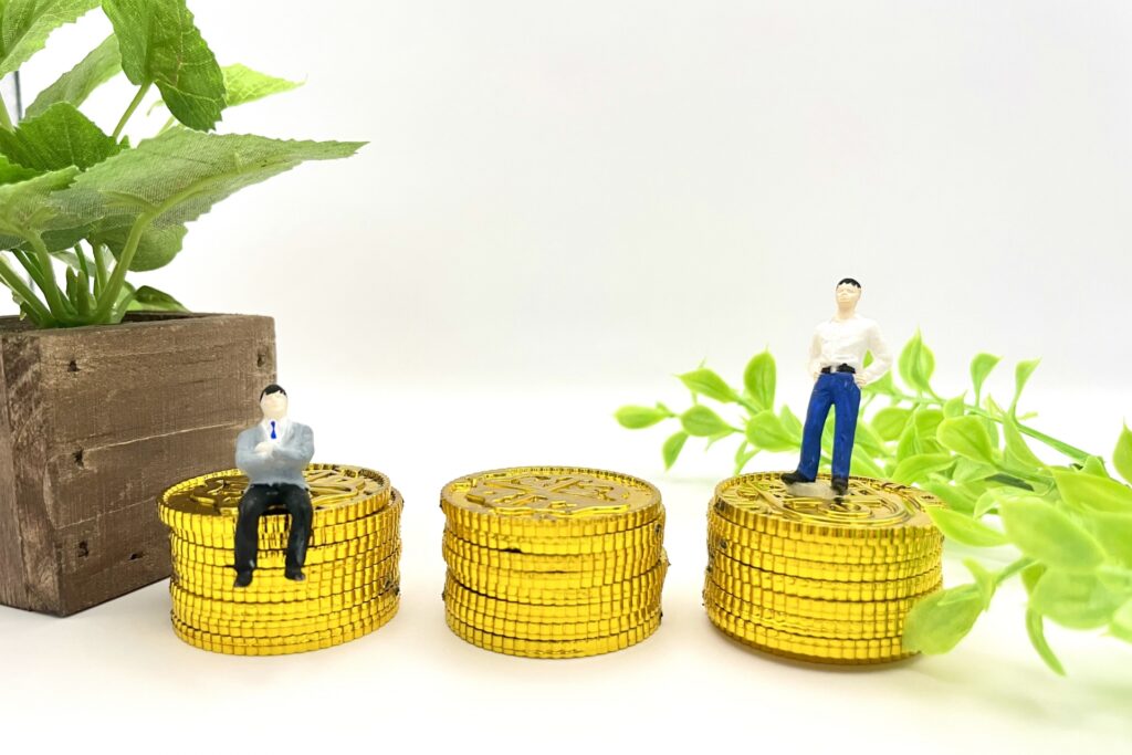 積まれた硬貨の上にミニチュアの人形が乗っている